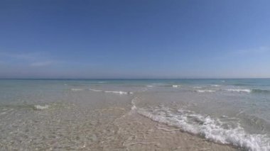 Kristal berrak sığ su ve mavi gökyüzü ile beyaz kum ağır çekim