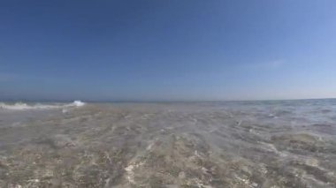 Kristal berrak sığ su ve mavi gökyüzü ile beyaz kum ağır çekim