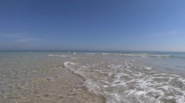 Kristal berrak sığ su ve mavi gökyüzü ile beyaz kum ağır çekim
