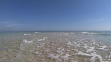 Kristal berrak sığ su ve mavi gökyüzü ile beyaz kum ağır çekim