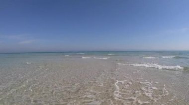 Kristal berrak sığ su ve mavi gökyüzü ile beyaz kum ağır çekim