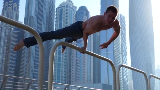 Gespierde man doet workout op straat met stadsgezicht van wolkenkrabbers op de achtergrond in Dubai. Concept van gezonde levensstijl en moderne — Stockvideo