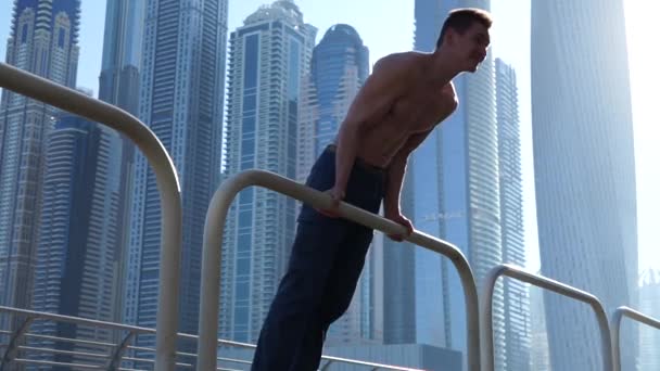 Izmos ember edz az utcán, felhőkarcolókkal a háttérben Dubaiban. Az egészséges életmód és a modern koncepció — Stock videók