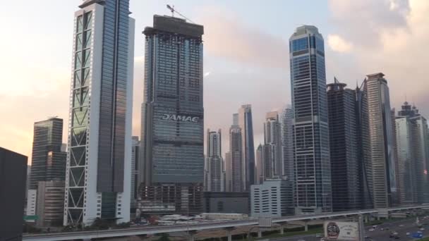 DUBAI FINANCIAL CENTER,UNITED ARAB EMIRATES FEBRUARY, 2020: Busy Sheikh Zayed Road, metro railway and modern skyscrapers around in luxury Dubai city — Stock Video