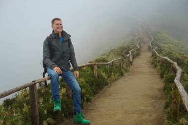 Genç bir adam yolun kenarında oturuyor.