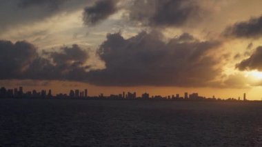 Gün batımında Miami Florida. Denizden bir video. Aydınlatılmış binaların renkli ufuk çizgisi