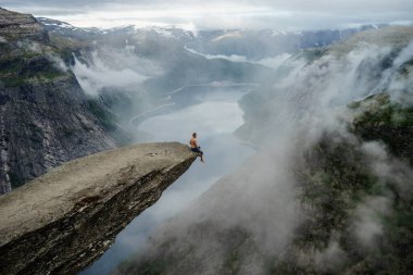 Uçurumun kenarında oturan cesur adam Trolltunga. Norveç