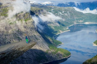 Jimnastikçi elleriyle kenarındaki fiyort yakınındaki Trolltunga arka planda tutuyoruz. Norveç