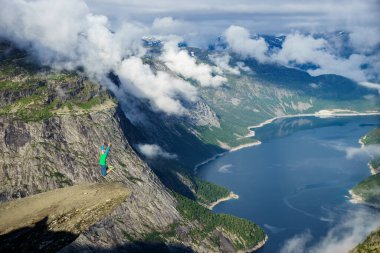 Genç adam atlamak kenarında Trolltunga. Norveç