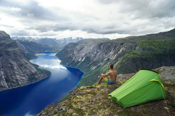 Norwegian fjord landscape with camping tent and young traveller. peace of mind concept