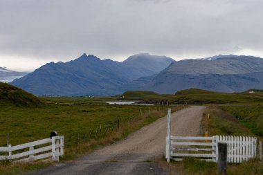 İzlanda 'daki fırtınalı bulutlar sırasında tarladaki çiftliğin kapısı..