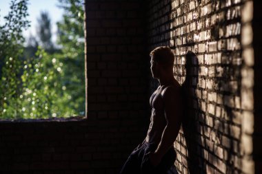 Terk Edilmiş Binanın İçindeki Kaslı Üstsüz Genç Adam. Özelliğe bakma kavramı 