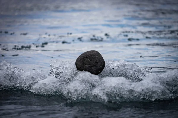 Small round black rock floating on icebergs, Iceland. concept of black sheep and loneliness