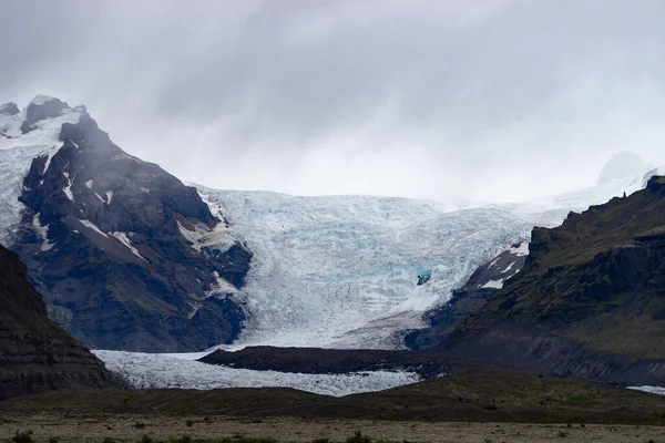 Ледник с золой во льду с талой водой и исландским ландшафтом — стоковое фото