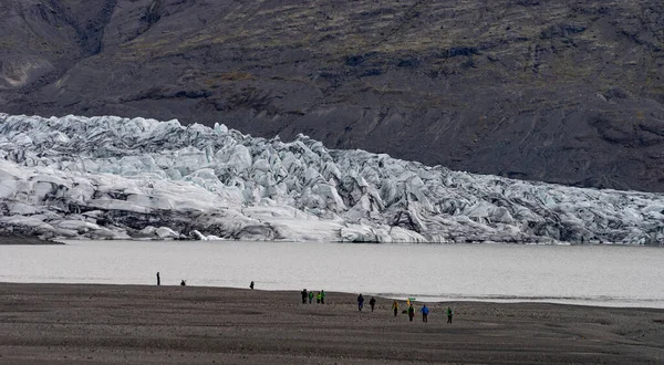 Ледник с золой во льду с талой водой и исландским ландшафтом — стоковое фото
