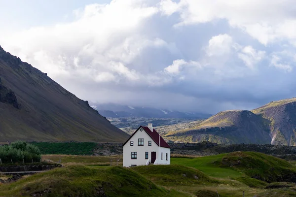 Farmhouse on hill in Iceland with cloudy sky and nice view on background — Stockfoto
