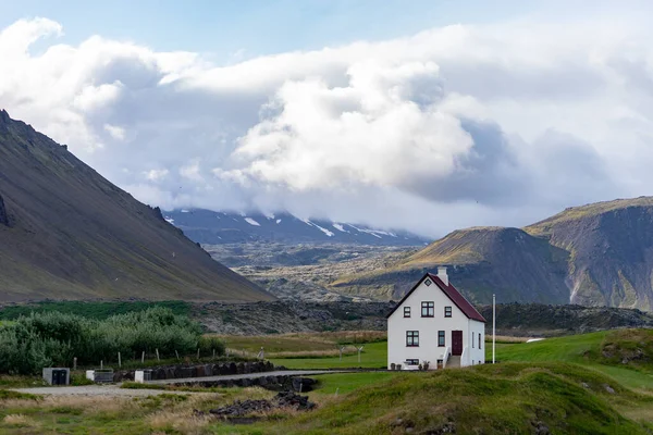 Boerderij op heuvel in IJsland met bewolkte lucht en mooi uitzicht op de achtergrond — Stockfoto