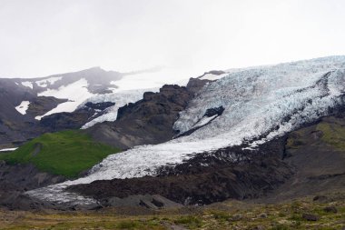 Buzul, kül ve yeşil çimlerle İzlanda 'nın güzel manzarası