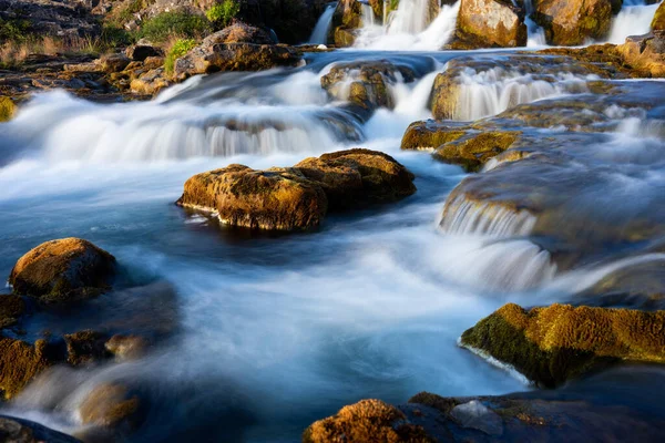 Larga exposición de un pequeño arroyo que fluye suavemente sobre rocas redondeadas — Foto de Stock