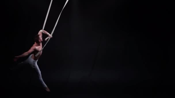 Muscular circus aerialist on the aerial straps in black studio — Stock Video