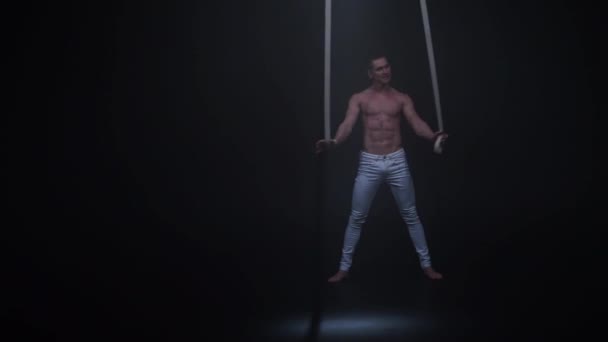 Aerialista de circo muscular nas alças aéreas em estúdio preto — Vídeo de Stock