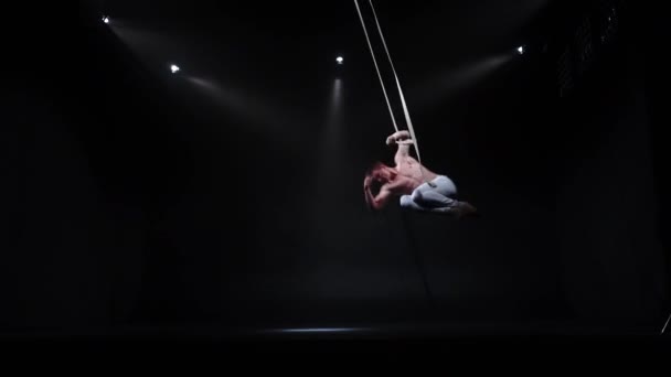4k Aerialista de circo muscular en las correas aéreas en estudio negro — Vídeos de Stock