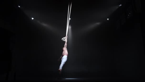4k Мускулистый циркач-эстрадист на воздушных ремнях в черной студии — стоковое видео
