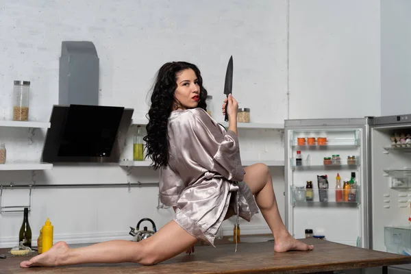 Flexible sexual woman sitting on the table and leaking knife ...