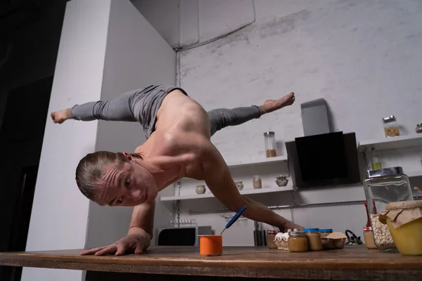 L'homme musclé se tient sur les mains dans la cuisine et mange du yaourt. Concept de mode de vie sain et d'alimentation biologique — Photo