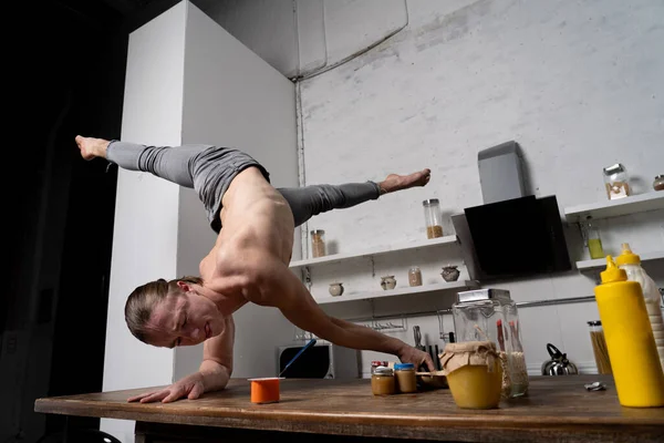 L'homme musclé se tient sur les mains dans la cuisine et mange du yaourt. Concept de mode de vie sain et d'alimentation biologique — Photo