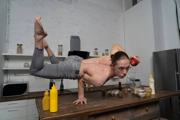 Musclé homme debout sur une main dans la cuisine et bouteille d'équilibre avec souse. concept de cuisine créative . — Photo