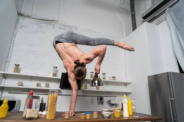肌肉发达的男人一只手扶着水壶站在厨房里.厨房里的概念创意 — 图库照片