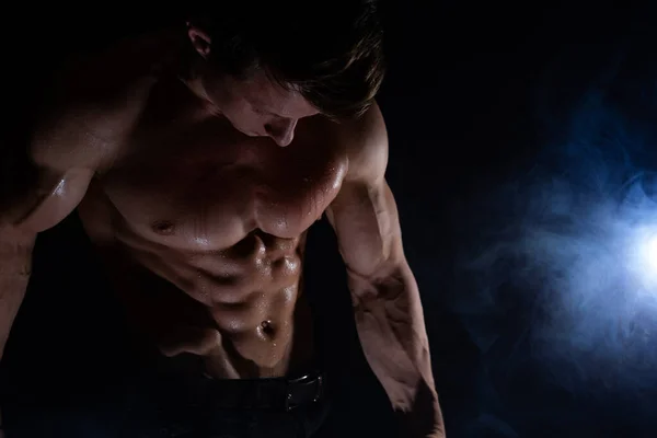 Homem musculoso mostrando músculos isolados no fundo preto. Conceito de estilo de vida saudável — Fotografia de Stock