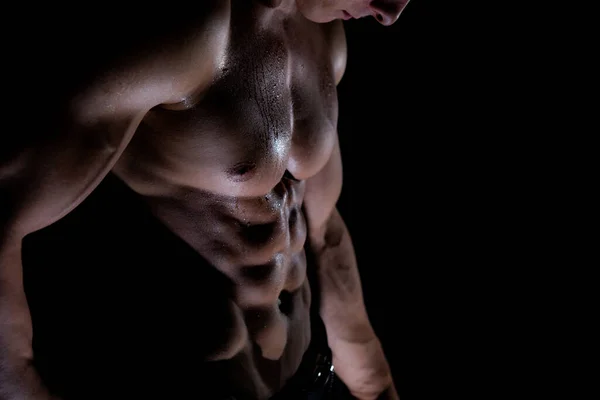 Hombre musculoso mostrando músculos aislados en el fondo negro. Concepto de estilo de vida saludable —  Fotos de Stock