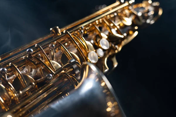 Golden shiny alto saxophone on black background with smoke. copy space