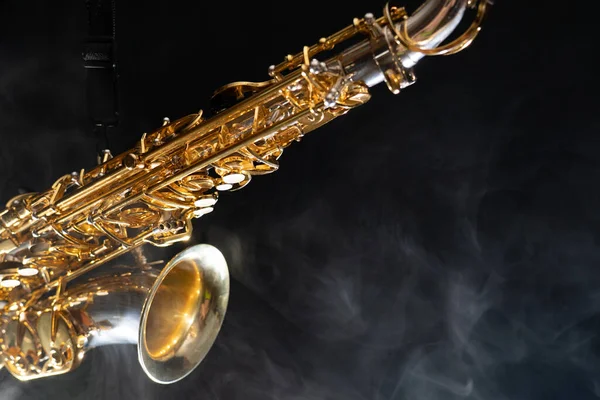 Golden shiny alto saxophone on black background with smoke. copy space