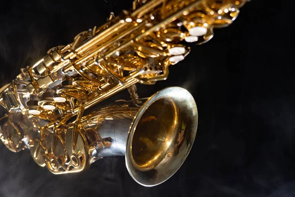 Golden shiny alto saxophone on black background with smoke. copy space