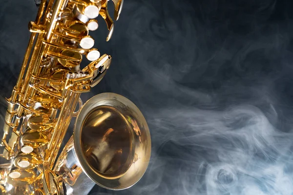 Saxofón alto dorado brillante sobre fondo negro con humo. espacio de copia — Foto de Stock