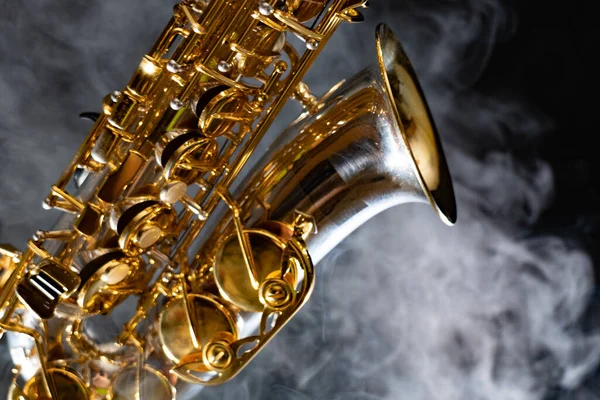 Saxofón alto dorado brillante sobre fondo negro con humo. espacio de copia —  Fotos de Stock