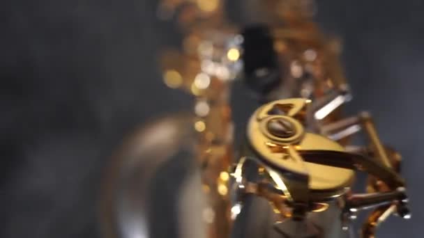 Golden shiny alto saxophone slowly move on black background with smoke — Stock Video