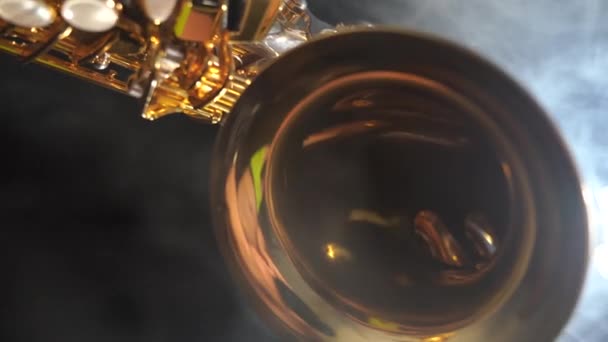 Золотий блискучий альт саксофон повільно рухається на чорному тлі з димом — стокове відео