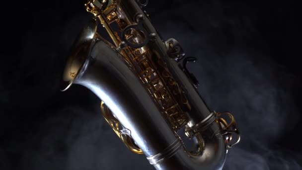 Golden glänsande alto saxofon långsamt flytta på svart bakgrund med rök — Stockvideo