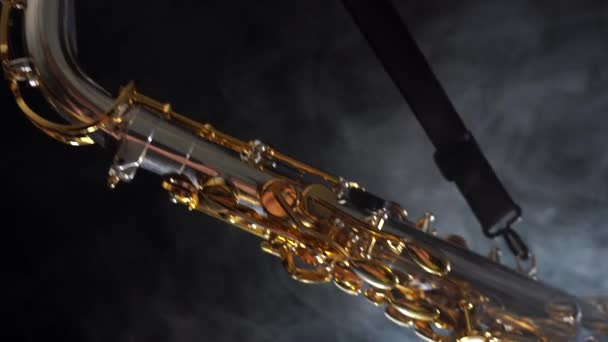 Saxofone alto brilhante dourado move-se lentamente sobre fundo preto com fumaça — Vídeo de Stock