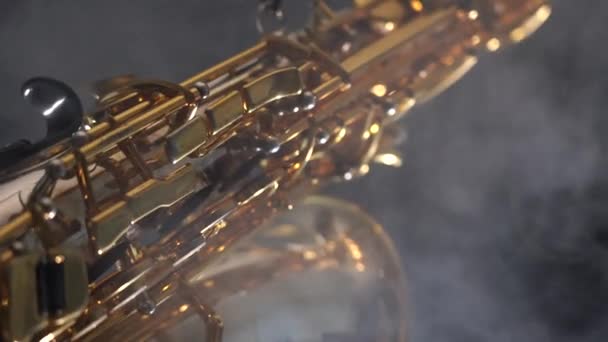 Saxophone alto brillant doré se déplace lentement sur fond noir avec de la fumée — Video