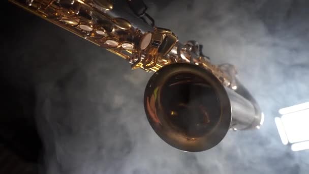 Golden shiny alto saxophone slowly move on black background with smoke — Stock Video