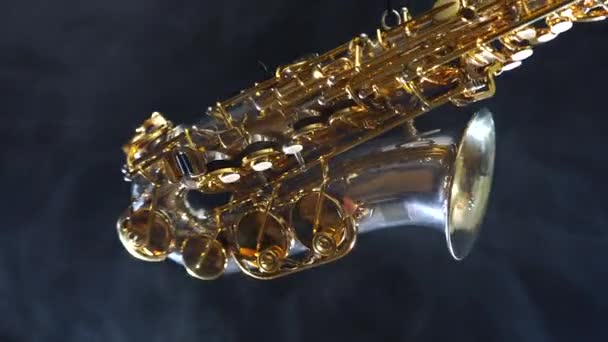 Złoty błyszczący saksofon altowy powoli porusza się na czarnym tle z dymem — Wideo stockowe