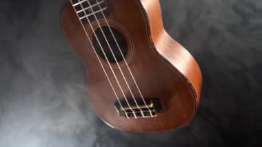 Kırmızı ahşap Hawaii gitarı siyah arkaplanda dumanla izole edilmiş.