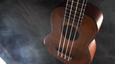 Kırmızı ahşap Hawaii gitarı siyah arkaplanda dumanla izole edilmiş.