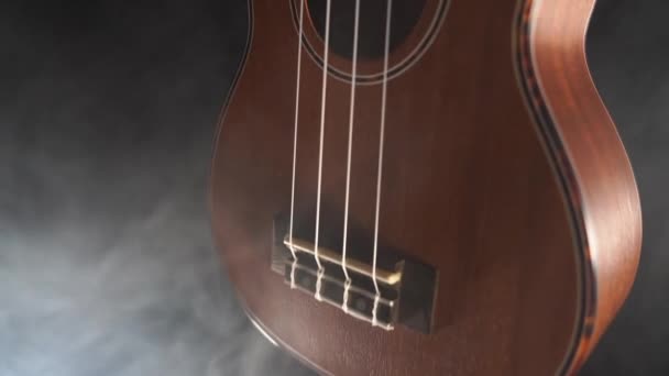Rood hout Hawaii ukelele gitaar geïsoleerd tegen zwarte achtergrond met rook — Stockvideo