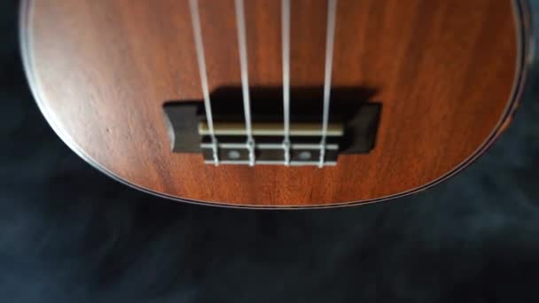 Rote Holz Hawaii Ukulele Gitarre isoliert vor schwarzem Hintergrund mit Rauch — Stockvideo